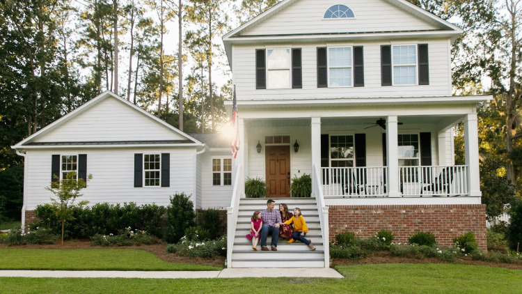 Family sitting on the steps of their house with beautiful newly installed white siding.