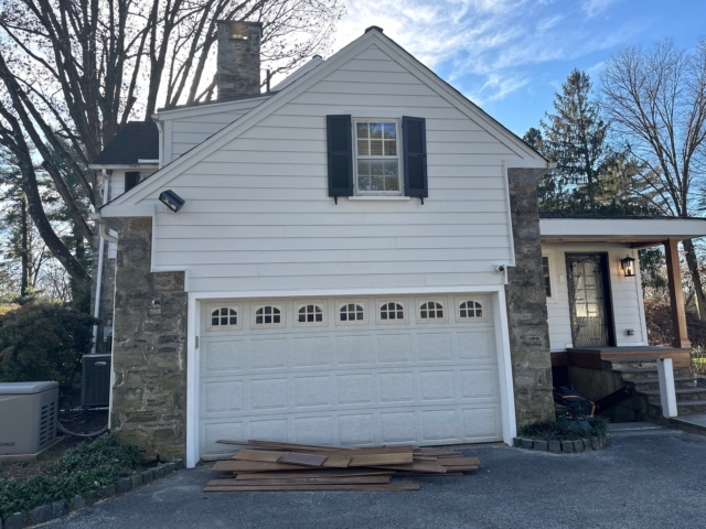 Garage exterior on a Gladwyne PA home with white James Hardie siding, stone accents and finished trim