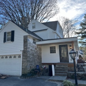 Finished Gladwyne PA home exterior with white James Hardie siding, stone chimney accents, updated porch details and clean curb appeal