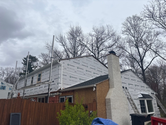 Exterior renovation in progress in Yardley, PA with scaffolding, exposed sheathing, and James Hardie weather barrier around the home. Exterior renovation in progress in Yardley, PA with scaffolding, exposed sheathing, and James Hardie weather barrier around the home.