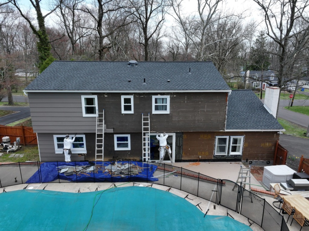 Aerial rear view showing siding removal in progress with exposed sheathing, and ladders at the Yardley, PA home by Porter Exterior