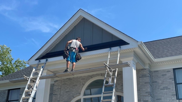 Porter Family Exteriors contractor installing a black metal roof accent above the home’s front entrance