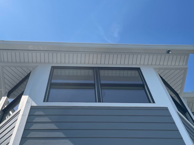Upper bay windows finished by Porter Family Exteriors with black frames, white trim, and Gray Slate siding