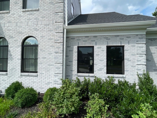 Porter Family Exteriors window replacement featuring black arched and rectangular windows against white brick